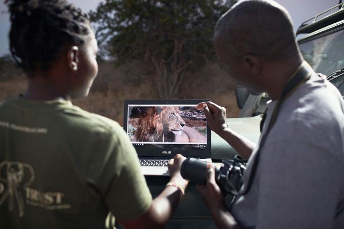 Une patrouille anti-braconnage consulte des photographies de lion sur un ordinateur.